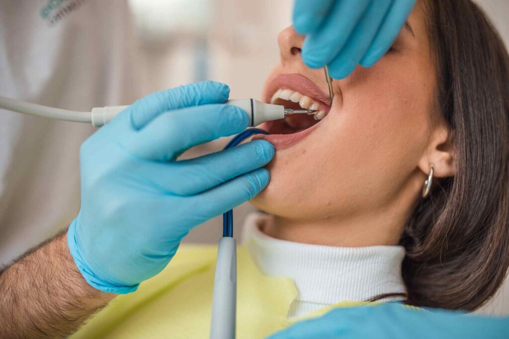 Dentist performing professional teeth cleaning with scaler and mirror in Highland, IN