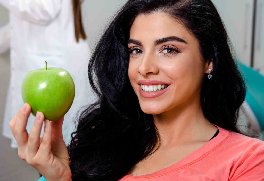 A woman with a green apple at the dental clinic, promoting oral & overall wellness in Highland, IN