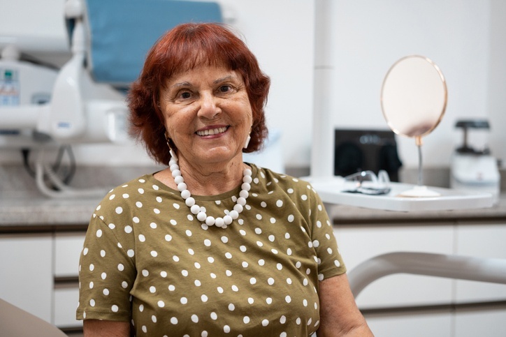 A senior in a dental office after cosmetic treatment, showing comfort & confidence in Highland, IN.