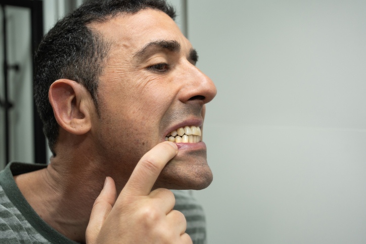 A person inspecting his teeth to check for plaque buildup and oral hygiene in Highland, IN