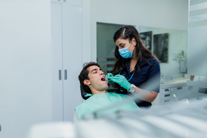 Young female dentist checking her patients teeth.