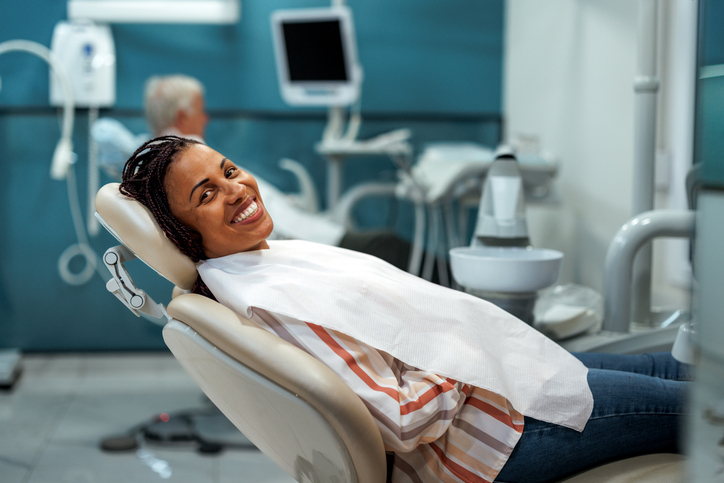 Smiling woman posing for camera while laying at dentist's office